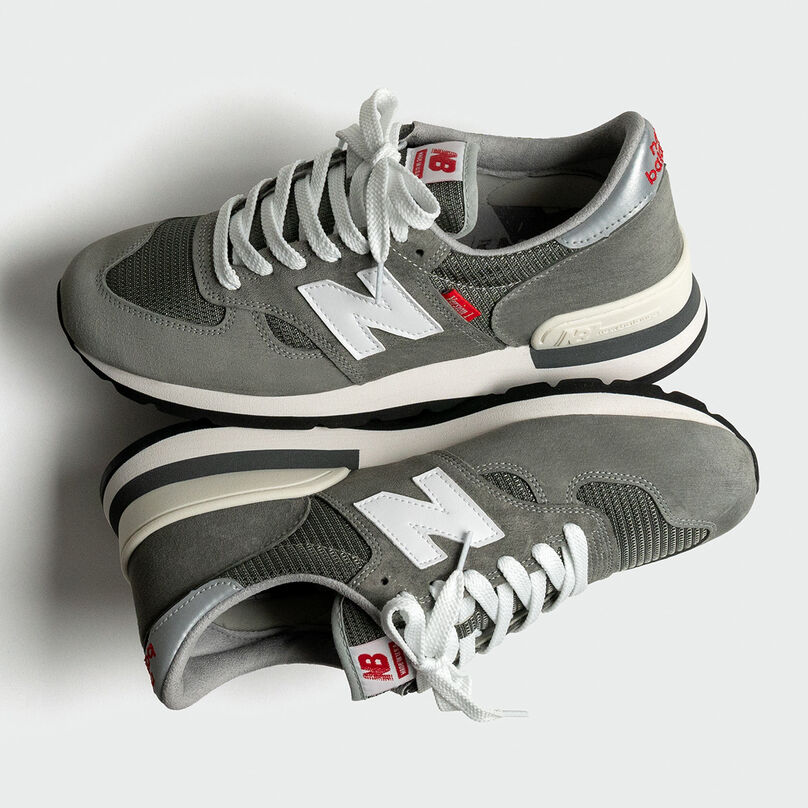 Overhead view of a pair of grey NB 990 Version 1 sneakers on a light grey background