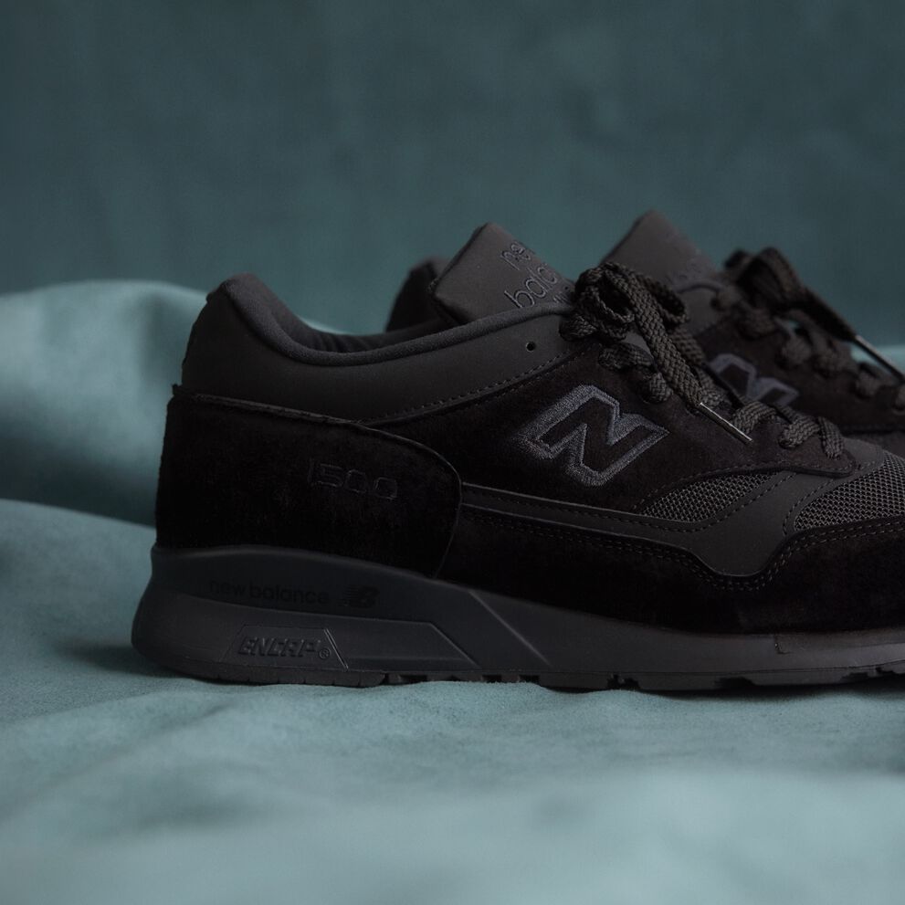 A close up view of the heel of a New Balance Made in UK sneaker on a flowing blue sheet backdrop.  