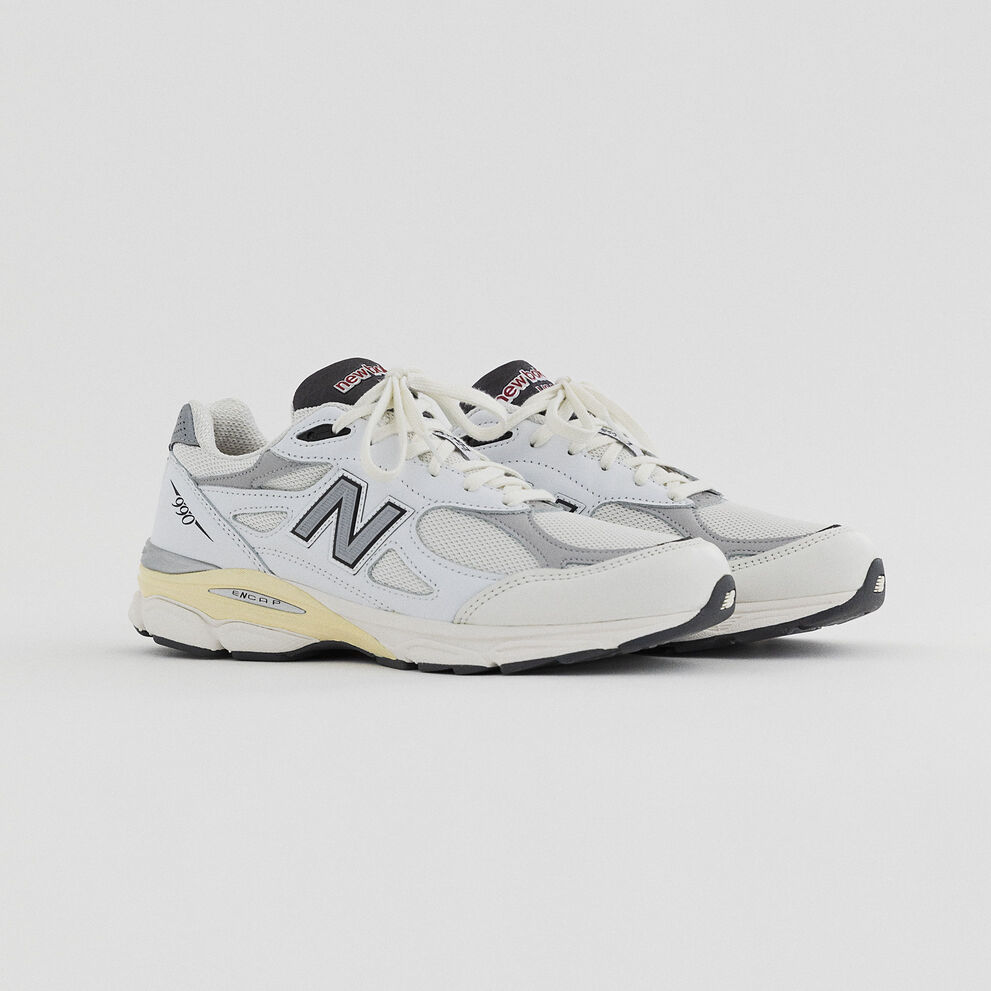 A pair of white 990v3 pointing to the right from the upcoming MADE Seasonal collection on a grey background.