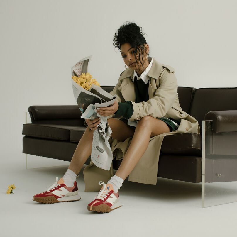 Woman holding a bouquet of flowers, while sitting on a leather couch, wearing red and yellow XC-72 shoes