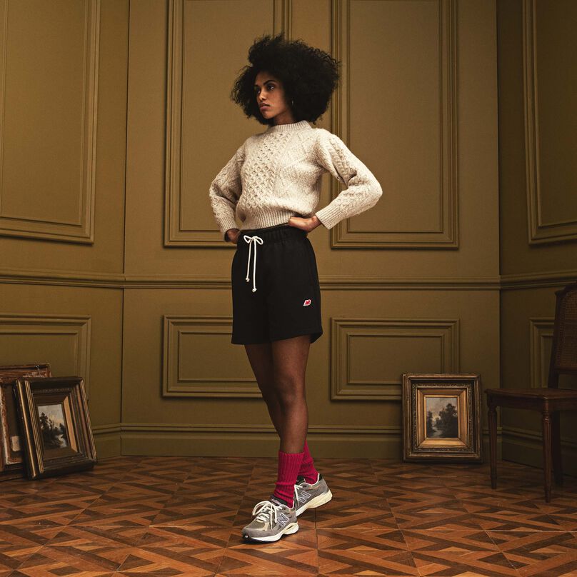 Woman standing in a beautiful indoor environment with her hands on her hips wearing MADE in USA apparel and the grey 990v3.