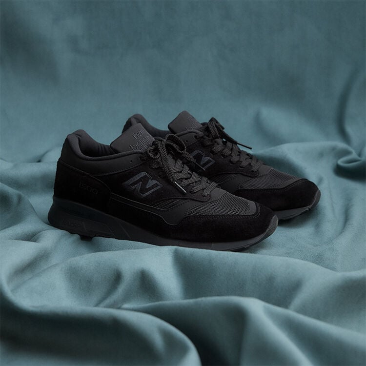 A pair of New Balance Made in UK sneakers on a flowing blue sheet backdrop.  